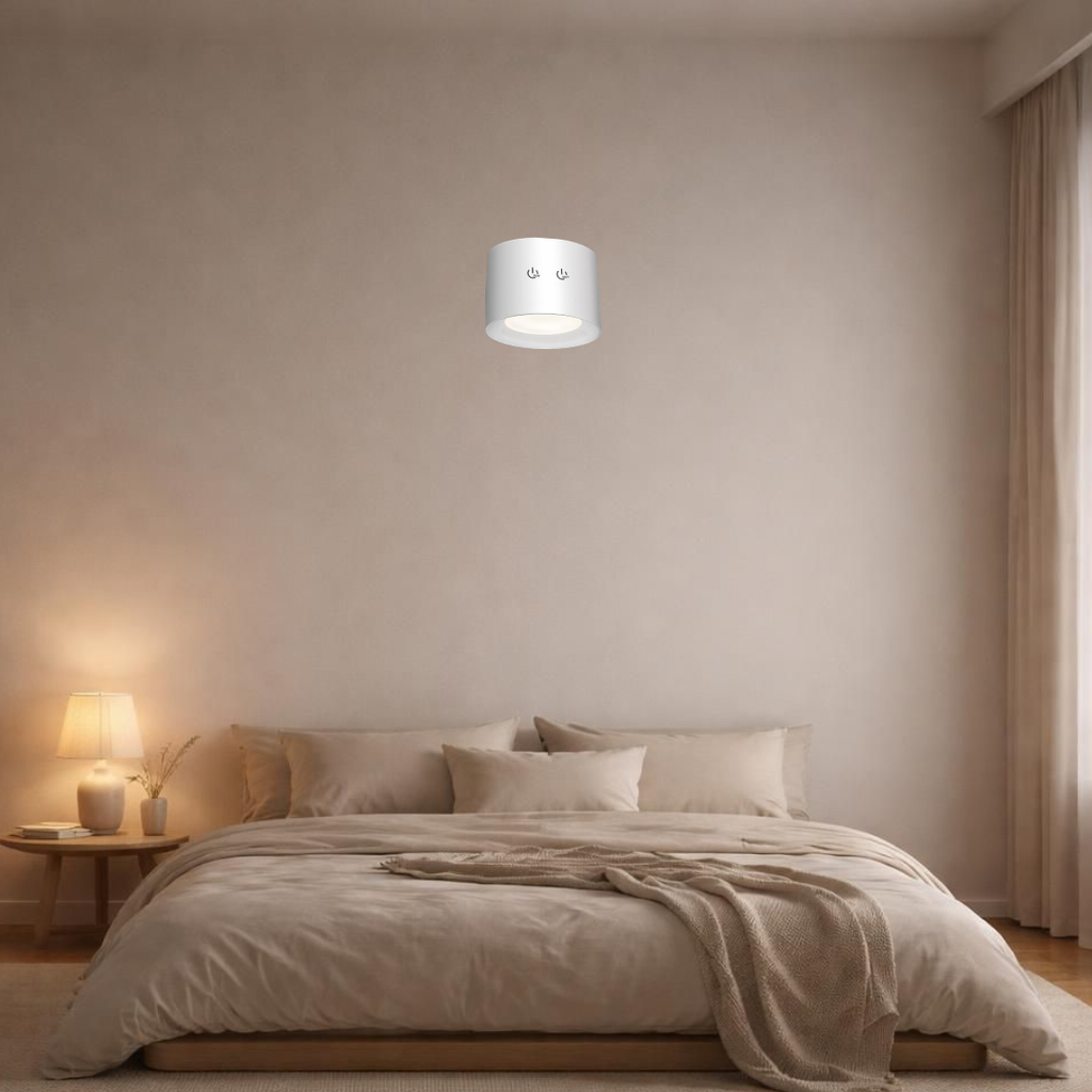 Rechargeable LED wall lamp mounted above a bed in a minimalist bedroom, casting warm ambient light