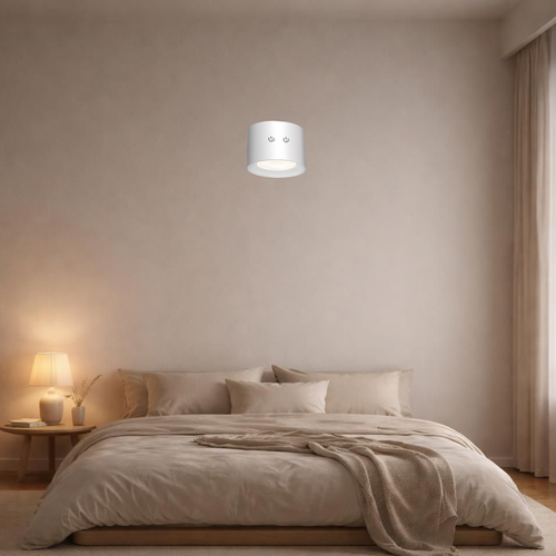 Rechargeable LED wall lamp mounted above a bed in a minimalist bedroom, casting warm ambient light
